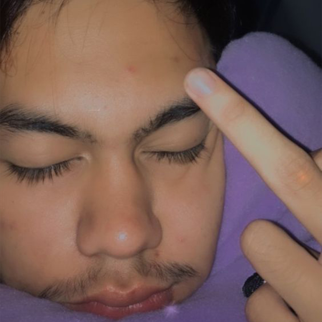 A closeup photo of Aljun sleeping and giving the camera the middle finger